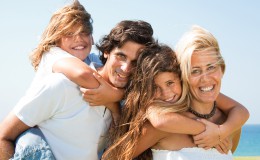 Couple giving children piggyback rides smiling